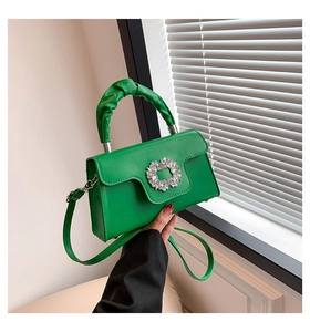 Detail of green leather handbag featuring a crystal buckle and pleated handle design