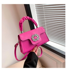 Detail of fuchsia crossbody bag featuring a rhinestone buckle and ruched handle design