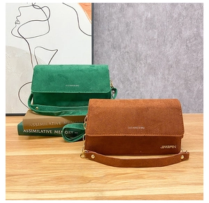 Nahaufnahme der matten Wildleder-Schultertaschen mit Kettenriemen in Smaragdgrün und Karamel