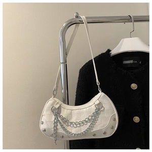 Close-up of white crocodile pattern shoulder bag with silver chains and rivets decoration