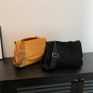 Minimalist faux suede shoulder bag with circular embossed detail and wide strap