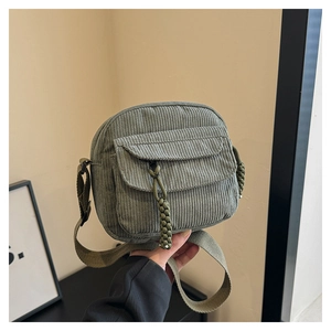 Detail of vintage green corduroy crossbody bag featuring a front pocket and braided zipper pull