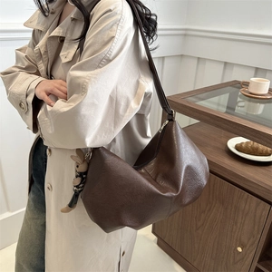 Retro large brown pleated hobo bag with cute bunny pendant shown in cozy cafe setting