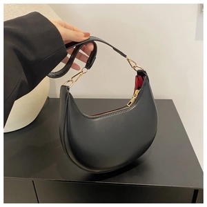 Detail showing the red fabric lining and gold zipper of the black crescent handbag