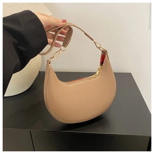 Close-up of crescent underarm bag in beige PU leather with elegant gold metal hardware