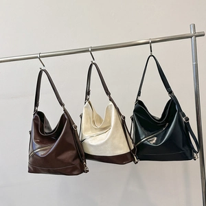 Tres bolsos tote retro grandes de cuero sintético en marrón, blanco y negro en un soporte