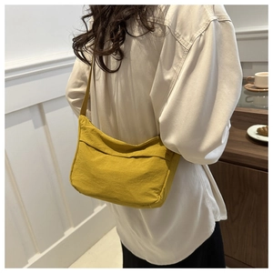 Close-up of bright yellow crescent tote bag worn as a shoulder bag on a white shirt