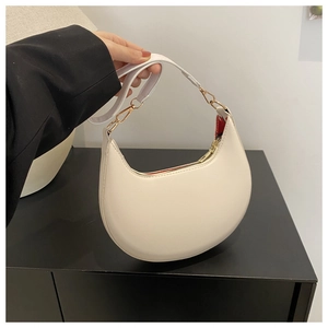 Detail of minimalist cream crescent bag with adjustable strap and light gold hardware