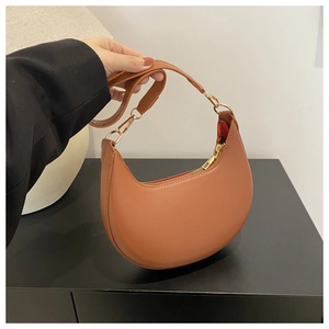 Detail of a brown leather crescent hobo bag with gold hardware and a smooth matte finish