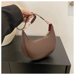 Detail of dark brown crescent bag showing smooth leather texture and red lining
