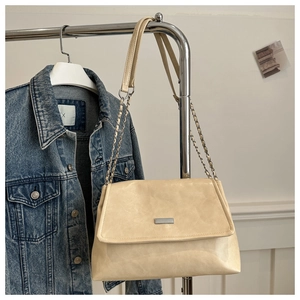 Detail of cream pleated leather bag with silver chain strap and metal buckle closure