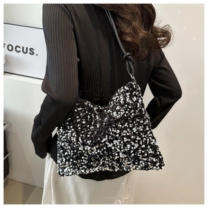 Close-up of sparkling black and white sequins on a shoulder bag with a knotted leather strap