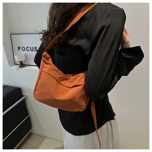 Détail du sac fourre-tout orange en nylon montrant sa texture souple et sa fine bandoulière