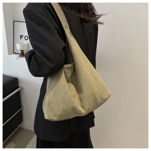 Detail of a large matte olive green tote bag showing soft suede texture on a model shoulder