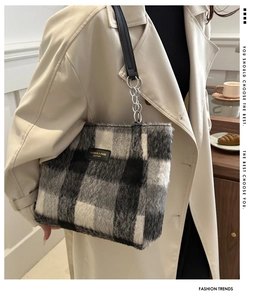 Detail of checkered woolen tote bag with leather logo patch and silver chain strap