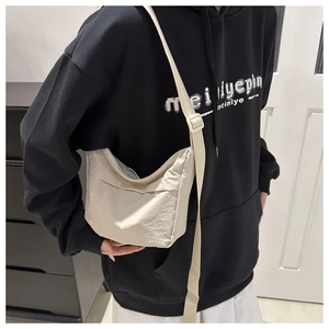 Détail du sac cabas beige avec bandoulière réglable et poche extérieure sur le devant