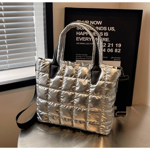 Detail of silver quilted tote bag showing square stitching and black strap texture