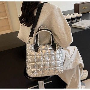 Quilted silver tote bag detail featuring metallic finish and black adjustable strap
