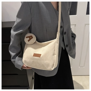 Detail of off-white corduroy tote bag with mini round pouch and brown fashion tag