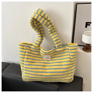 Detail of colorful striped plush tote bag with embroidered letters on soft fleece texture