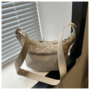 Gros plan du sac bandoulière en nylon beige avec sangle réglable près d'une fenêtre