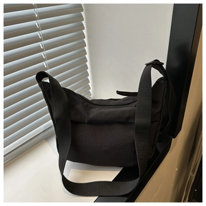 Détail du sac demi-lune noir minimaliste en nylon avec bandoulière large et fermeture éclair