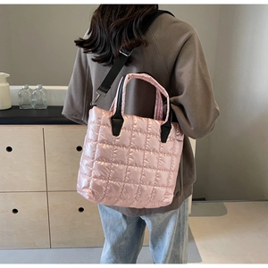 Back view of model wearing a pink quilted bucket bag with black contrasting straps