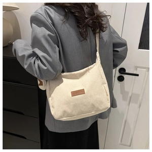 Detail of off-white corduroy tote bag showing striped texture and brown fashion label