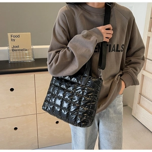 Detailed view of black quilted bucket bag with adjustable nylon strap worn by model