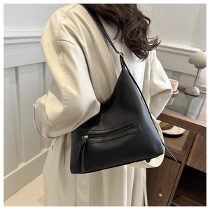 Detail of black lychee grain faux leather hobo bag with zipper on a trench coat