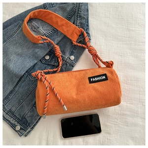 Detailed shot of orange corduroy bucket bag with rope strap and fashion label detail