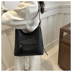 Detail of black lychee leather tote bag featuring a front zipper pocket and adjustable strap