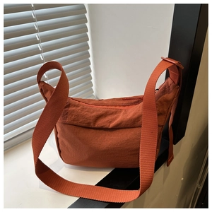 Détail du sac croissant en nylon rouge rouille montrant la texture lavée et la sangle