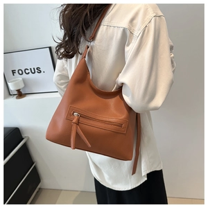 Detail of caramel tote bag showing lychee pattern texture and functional front zipper pocket