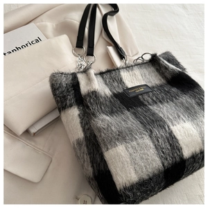 Close-up of black and white checkered plush tote bag with metal chain and leather strap