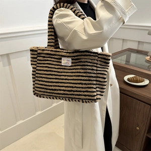 Sac cabas rayé en polaire noir et jaune porté par un mannequin dans un intérieur