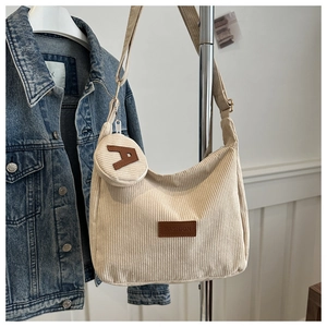 Detail of cream corduroy tote bag featuring a brown FASHION label and small coin purse