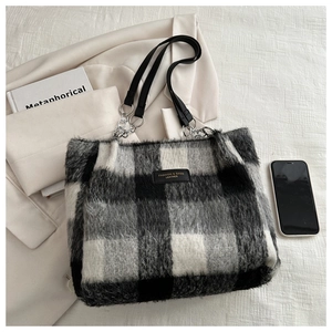 Close-up of wool plaid tote bag with luxury leather logo and stylish chain strap