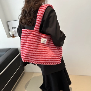 Sac cabas rayé en polaire rose et rouge porté par un mannequin dans un cadre moderne