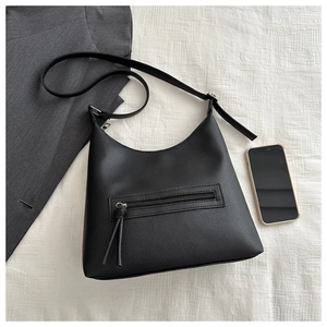 Flat lay of black lychee leather tote bag with tassel zipper and shoulder strap details