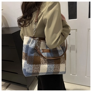 Detailed view of checkered wool tote bag featuring brown leather straps and silver chains