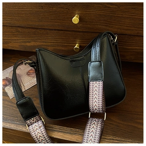 Detail of vintage black leather crescent bag with colorful geometric woven shoulder strap