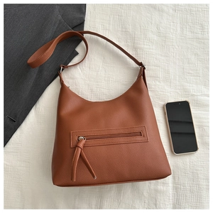 Detail of brown litchi pattern leather tote bag with functional zipper and shoulder strap