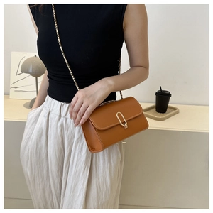 Close-up of caramel rectangle crossbody bag with gold oval lock and elegant chain strap