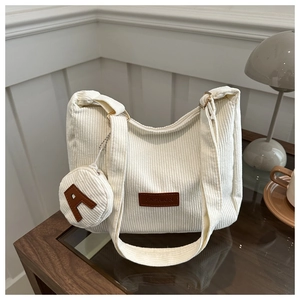 Detailed texture of off-white corduroy tote bag with fashion leather tag and small coin pouch