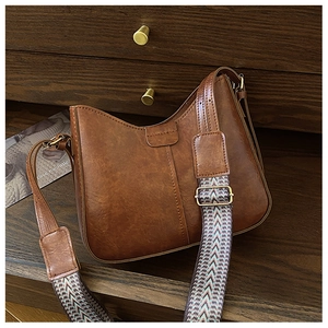 Detail of vintage brown PU leather bag featuring wide chevron pattern woven shoulder strap