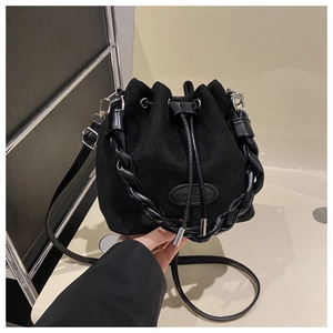 Detail of black suede bucket bag with woven handle, drawstring closure and silver hardware