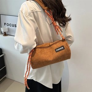 Brown corduroy cylinder crossbody bag with woven rope strap and fashion label on front