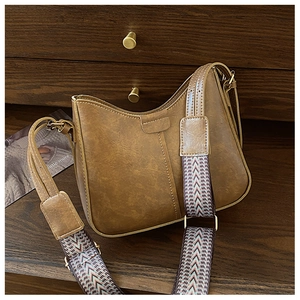 Close-up of vintage brown leather bag with colorful ethnic style woven wide shoulder strap