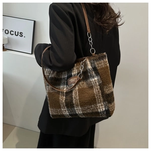 Detail of checkered woolen tote bag with leather logo tag and metal chain strap